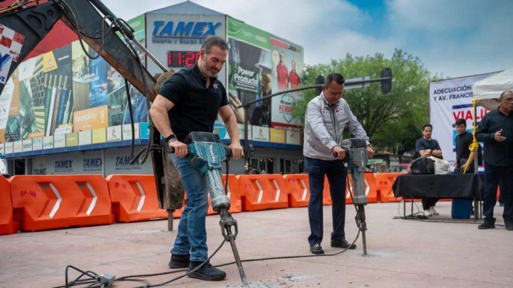 Two men operate jackhammers at an outdoor demo orange barriers lining the area with banners in the background   Informe Regio