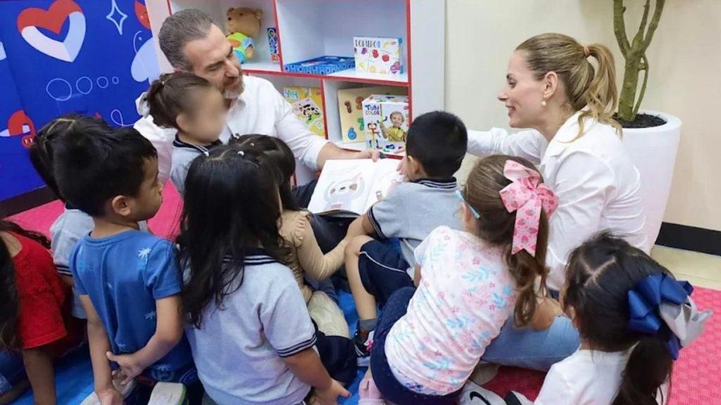 Two adults read a picture book aloud to a group of young children seated on the floor in a colorful room in a storytime setting   Informe Regio