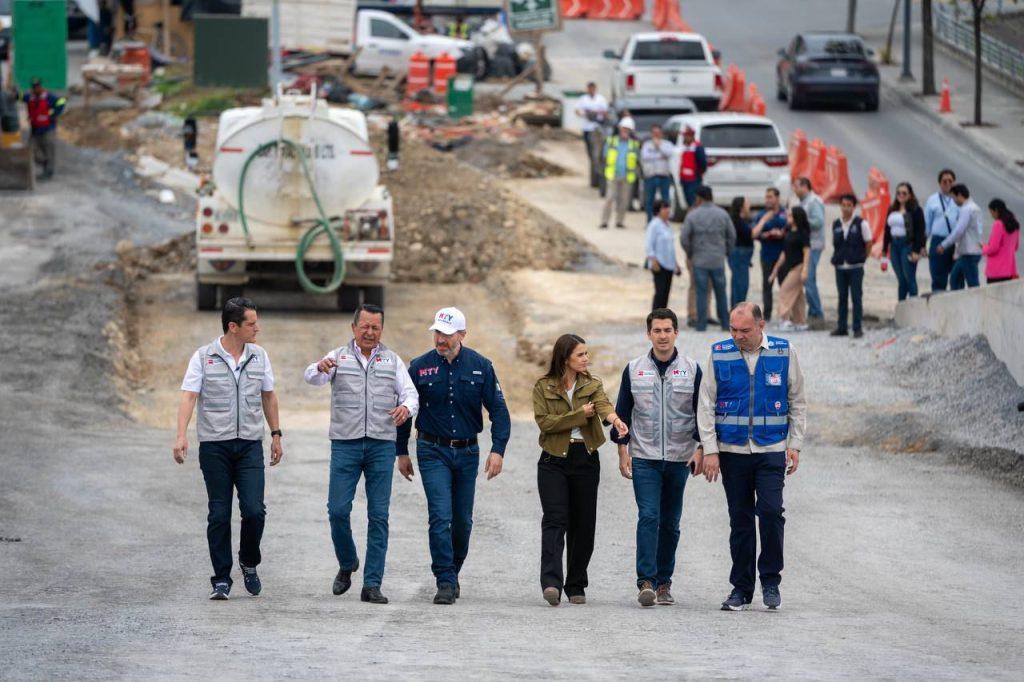 Group of officials walking on a construction site wearing vests with equipment and onlookers in the background   Informe Regio