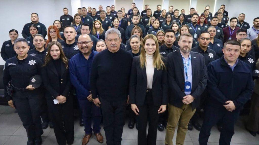 Group photo of a diverse team of uniformed officers and staff standing in a hallway facing the camera with a few foreground leaders in front   Informe Regio