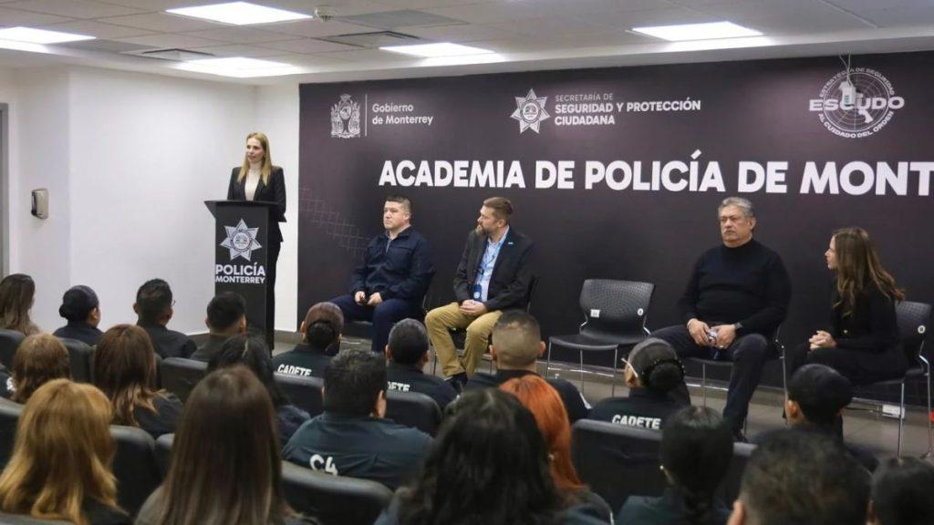 Speaker at a podium addressing cadets in a police academy with four panelists seated on stage and a large ACADEMIA DE POLICÍA DE MONTERREY backdrop   Informe Regio