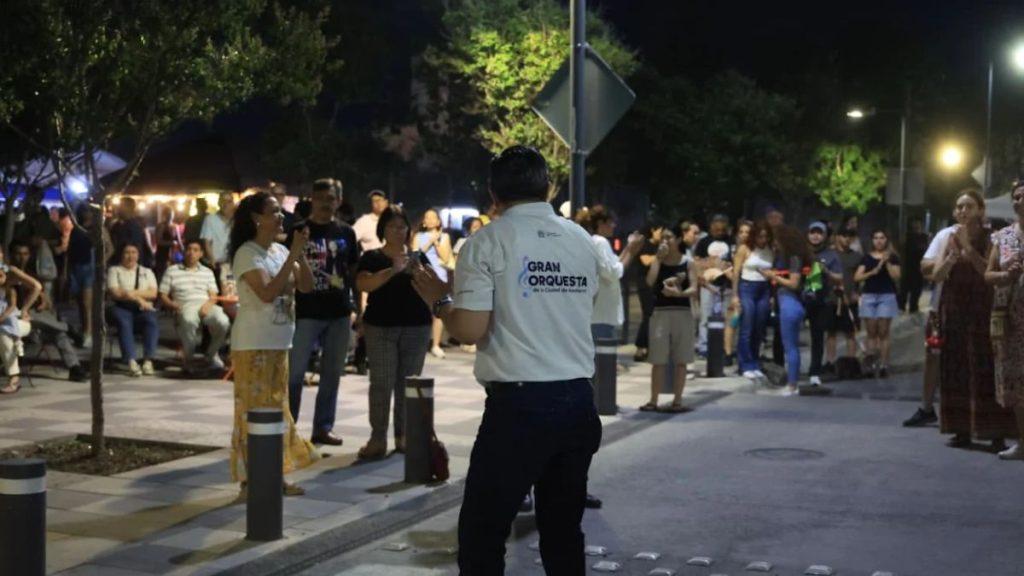 Nighttime street performance with a man in a white shirt labeled GRAN ORQUESTA facing a crowd   Informe Regio