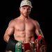 Fotografía de Canelo Álvarez sosteniendo los cinturones que ha ganado como boxeador y posando en un fondo negro   Informe Regio