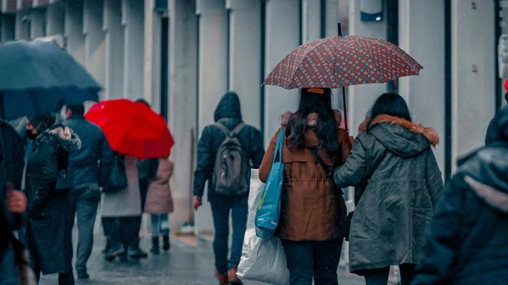 Personas caminando en la ciudad en medio de la lluvia usando paraguas y ropa de invierno   Informe Regio