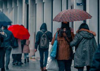 Personas caminando en la ciudad en medio de la lluvia usando paraguas y ropa de invierno   Informe Regio