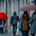 Personas caminando en la ciudad en medio de la lluvia usando paraguas y ropa de invierno   Informe Regio