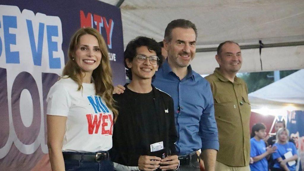 Group of four people smiling for a photo on a podium at an event with a large banner in the background   Informe Regio