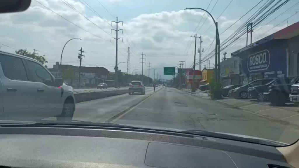 Street view from car white SUV on left storefronts and a large Rosco sign on the right daytime with power lines overhead   Informe Regio