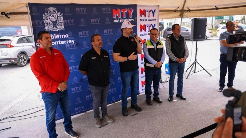 Quitar-obstáculos-viales-en-monterrey - Informe Regio Five men stand in a row under a blue event backdrop one wearing a cap speaks into a microphone while others listen a cameraman films from the right Informe Regio