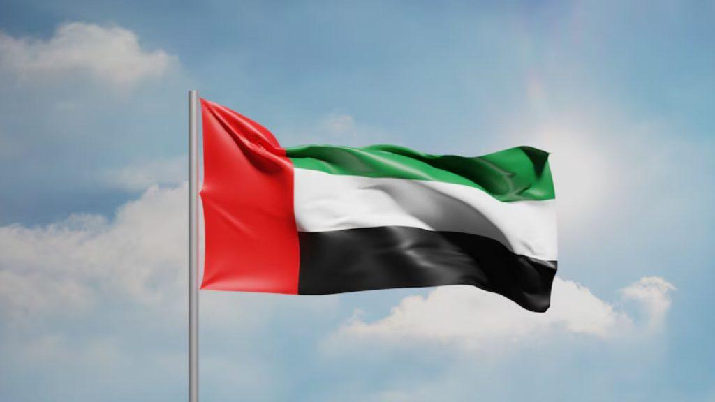 Waving United Arab Emirates flag on a flagpole against a cloudy blue sky