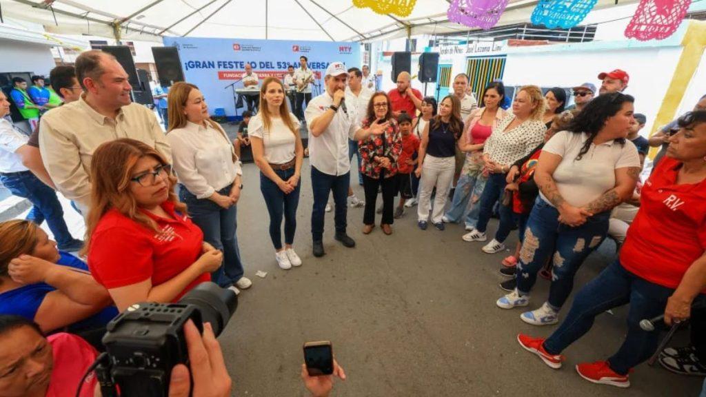 Group of people standing in a circle under a tent as a man with a microphone speaks to attendees a photographer is visible in the foreground collecting the scene   Informe Regio