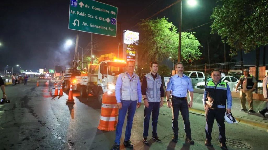 Nighttime road scene with four highway workers posing beside a tow truck and orange traffic cones illuminated by streetlights in the background   Informe Regio