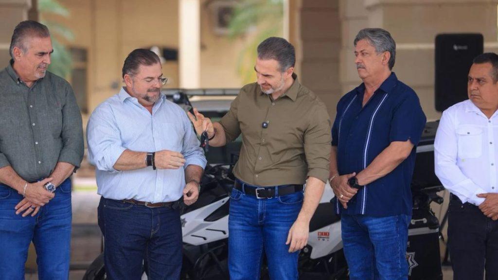 Five men in casual shirts stand outdoors around a white motorcycle one man shows a key or device to another while the group watches   Informe Regio