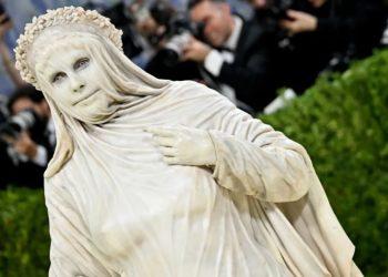 Person in a white marble like costume with a flower crown posing on a red carpet photographers in the background   Informe Regio