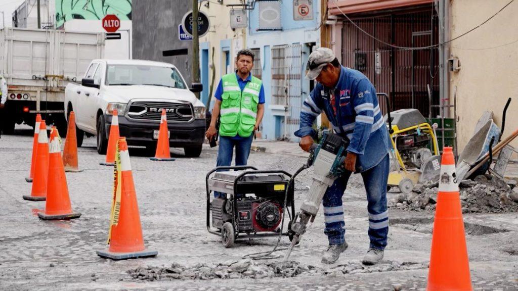 Road workers repair a pothole with a jackhammer surrounded by orange traffic cones and a generator nearby   Informe Regio