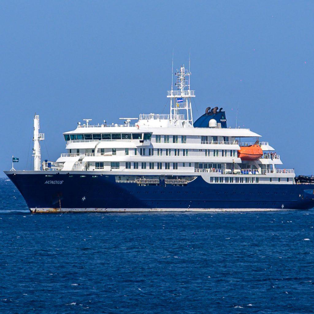 Side view of a large white cruise ship on calm blue sea with an orange lifeboat on the deck   Informe Regio