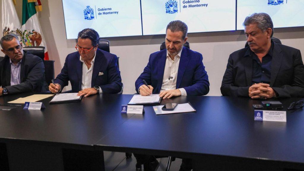 Four men in suits sit at a long conference table signing documents during a formal government meeting nameplates and a smartphone rest on the table with a Monterrey government backdrop   Informe Regio
