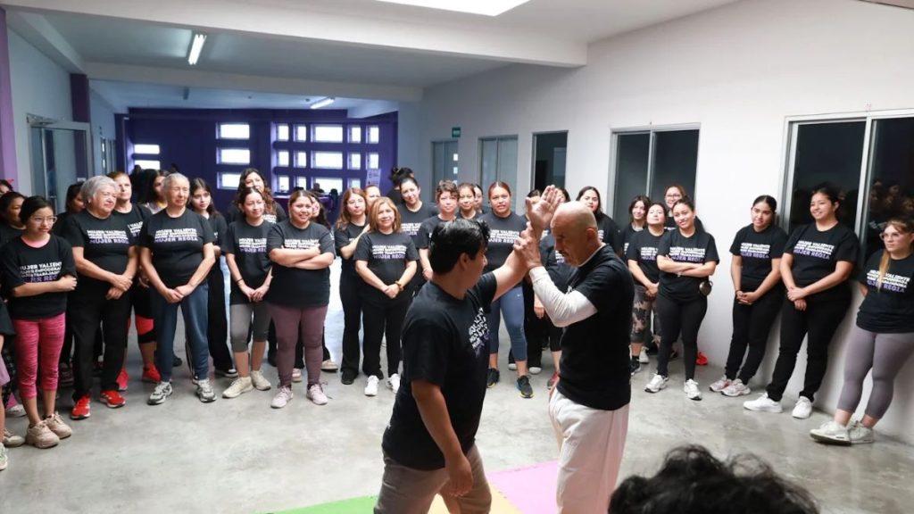 Group of people in a bright room wearing matching black shirts watching two men in the center give a high five   Informe Regio