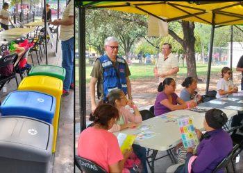 Row of colorful recycling bins beside a market-style seating area as volunteers run a park event under a canopy.