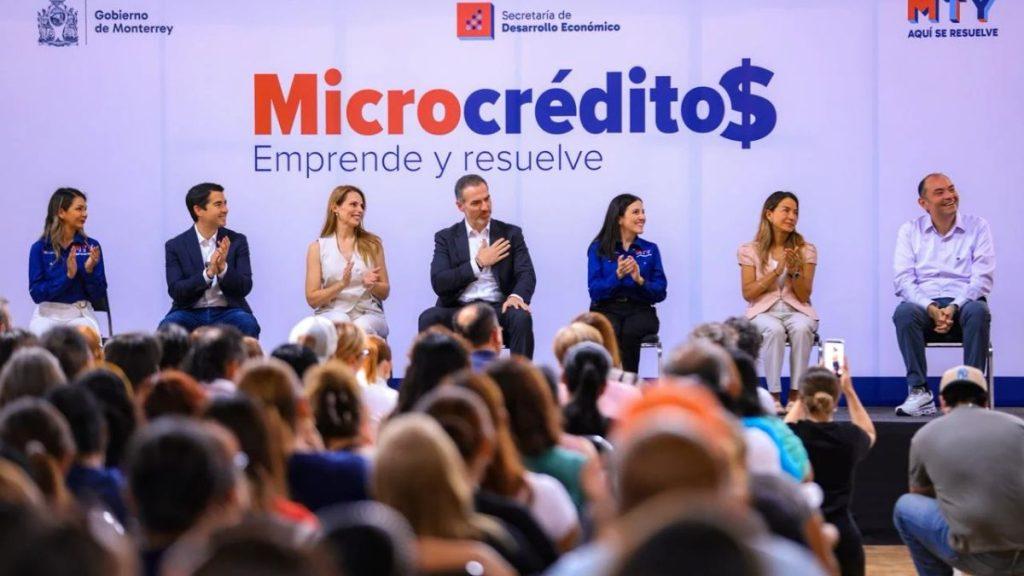 Panel discussion on microcredit benefits with seven speakers on stage and a large Microcrédito$ banner behind them   Informe Regio