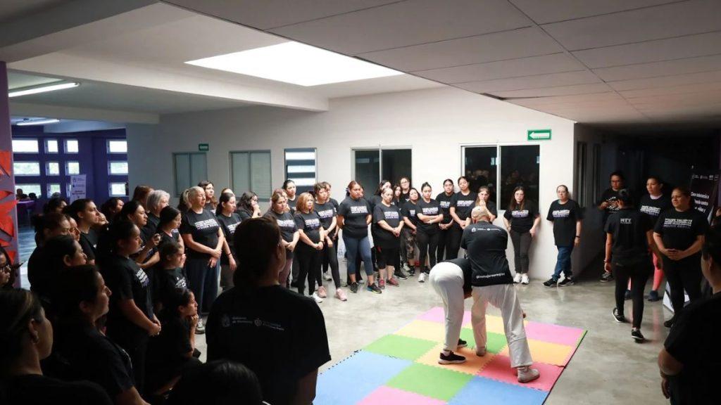 Group of participants forming a circle as two instructors demonstrate a self defense move on a colorful foam mat in a bright indoor space   Informe Regio