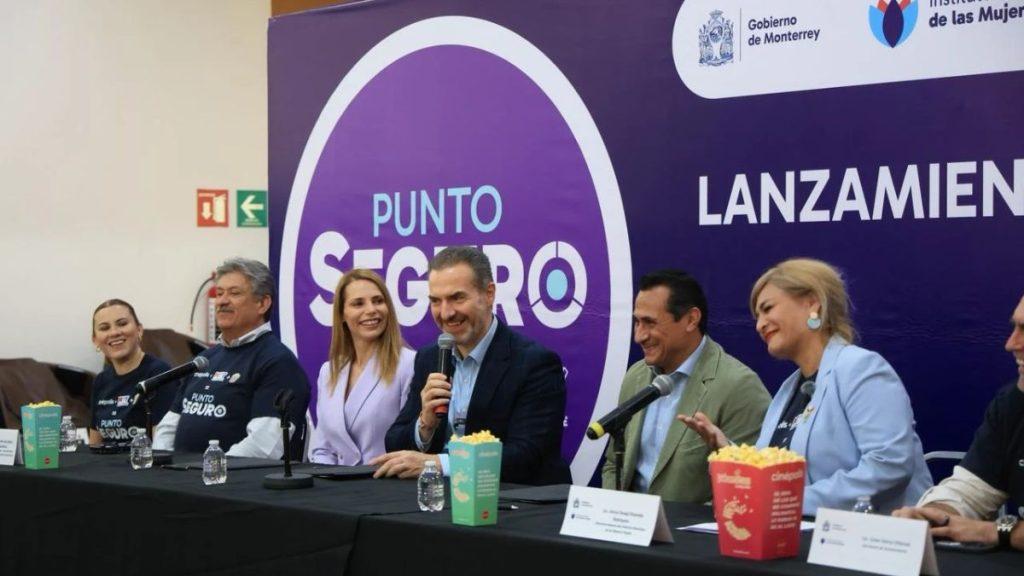 Panel of six people seated at a long table with microphones during a launch event for Punto Seguro with a purple backdrop bearing the logo and the word LANZAMIENT visible Snacks and name cards are on the table   Informe Regio