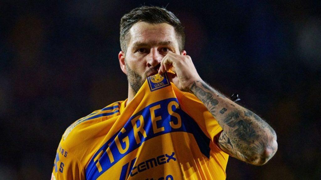 Male athlete in a yellow team jersey lifting and biting his shirt during a game against a dark background tattoos on arm visible   Informe Regio
