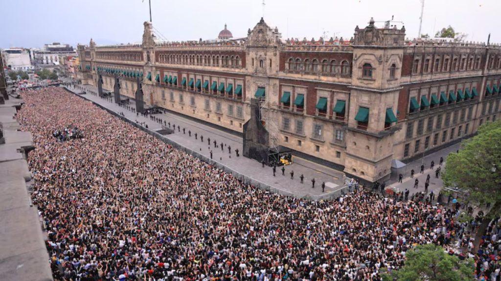 Huge crowd fills a city street in front of a long ornate brick building with green awnings   Informe Regio
