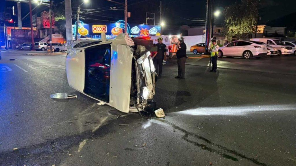 Automovilista-perdió-la-vida-tras-volcadura-en-monterrey - Informe Regio White SUV flipped on its side at night with responders on a neon lit city street inspecting the crash site Informe Regio