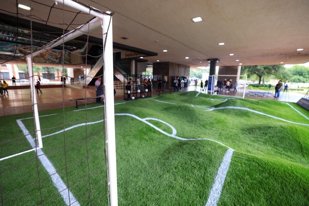 Indoor sports area with a soccer goal in the foreground artificial turf with white lines and people gathered in the background   Informe Regio