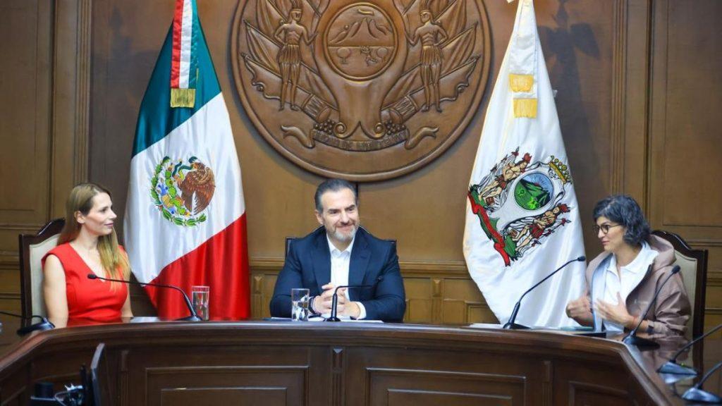 Three people sit at a wooden panel desk in a government chamber Mexico flag on the left and another flag on the right behind them   Informe Regio