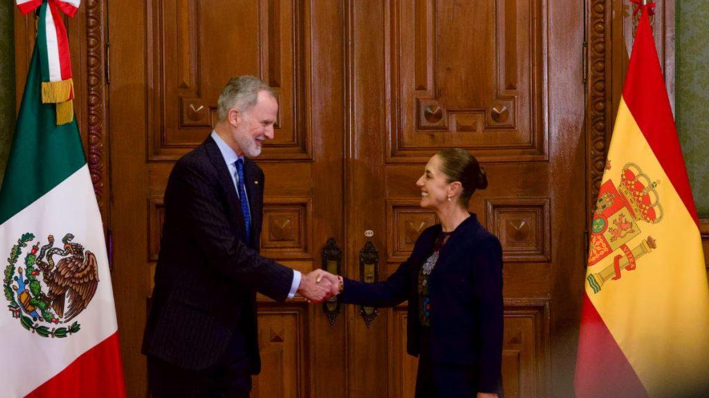 Two officials shake hands in front of ornate wooden doors with Mexican and Spanish flags on either side   Informe Regio