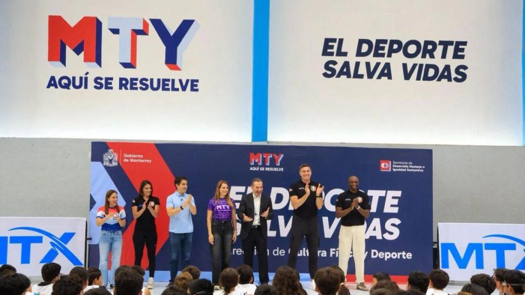 Entrenamiento-de-basquetbol-profesional-en-mty - Informe Regio Group of speakers on a gym stage clapping with MTY banners saying Aqui se resuelve and El deporte salva vidas Informe Regio
