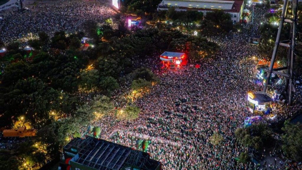Aerial view of a massive crowd at a nighttime outdoor concert with a red lit stage at center   Informe Regio