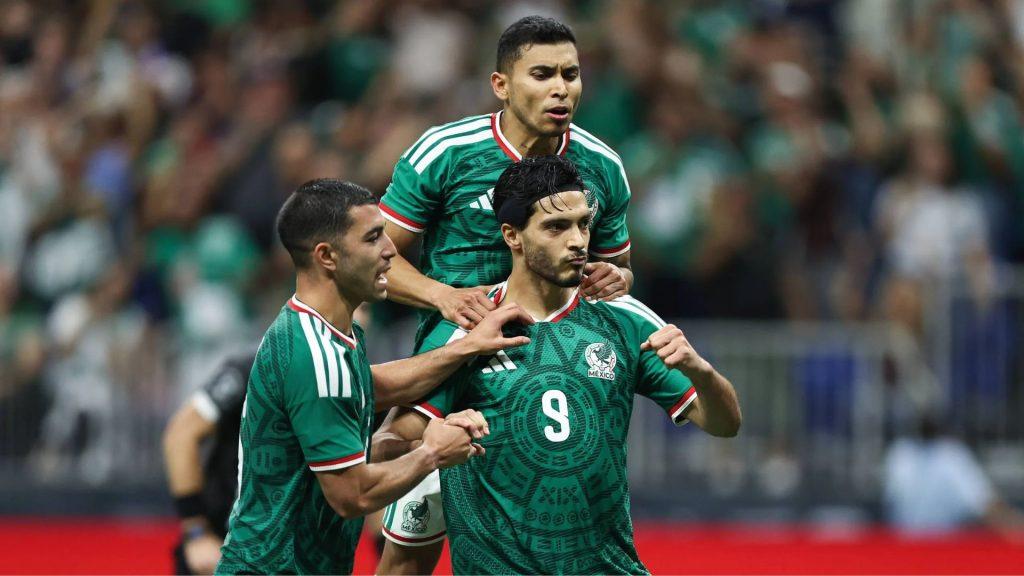 Three Mexico national soccer players celebrate a goal with one on anothers shoulders in green jerseys amid a blurred crowd   Informe Regio