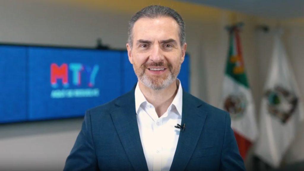 Male presenter in a dark blue suit and white shirt delivers a talk wearing a clip on microphone in a studio with a blue screen backdrop behind him   Informe Regio