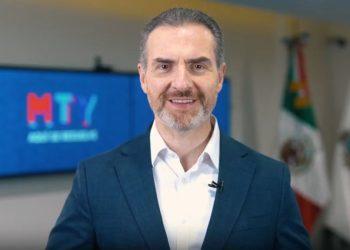 Smiling man in a navy suit delivers a video in a studio with an MTY logo on a screen behind him   Informe Regio