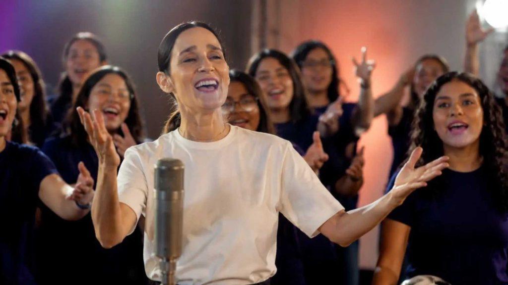 Julieta-venegas-recibe-criticas-por-la-nina-futbolista - Informe Regio Woman in a white shirt sings into a microphone with a cheering crowd behind her hands raised and smiling families in the background Informe Regio