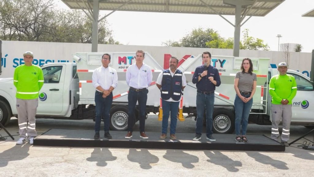 Seven people stand on a stage in front of white utility trucks during a ceremony or event   Informe Regio