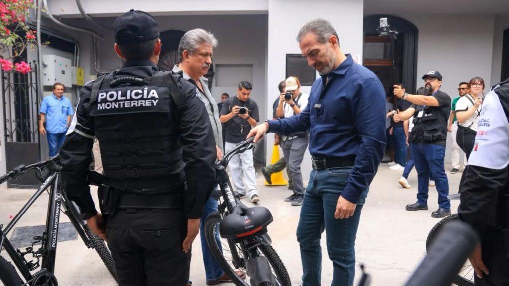 Man in a blue shirt inspects a black bicycle as police officers and photographers observe at a street event   Informe Regio