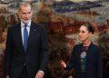 Two formally dressed individuals stand before a large mural of a historic battle scene   Informe Regio