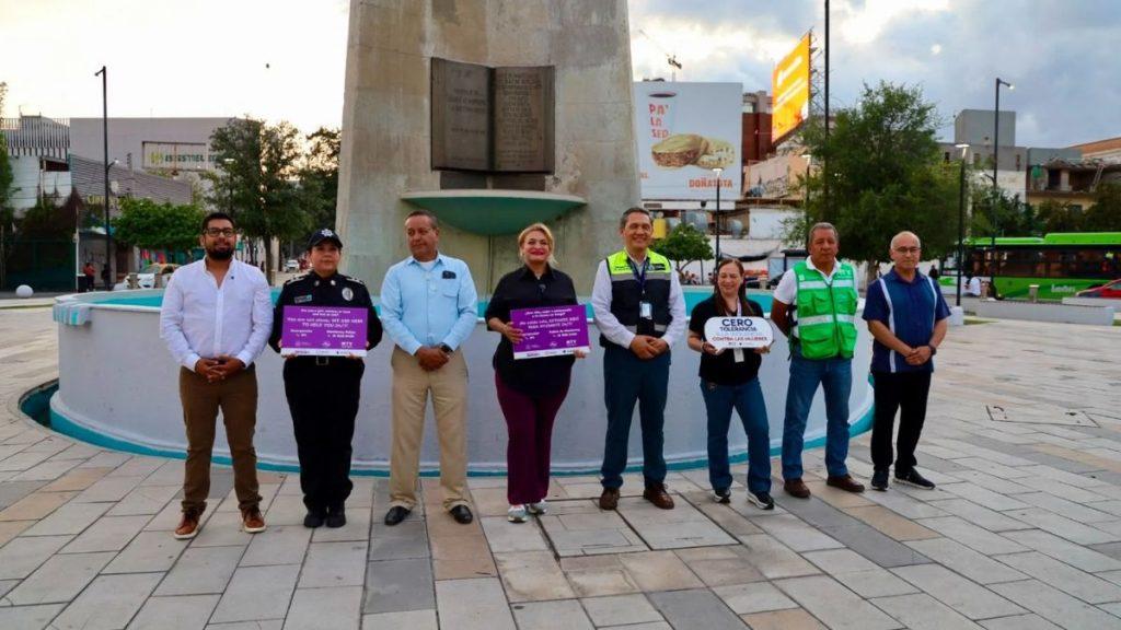 Group of nine adults standing in a public plaza in front of a concrete monumentfountain some holding purple posters about anti violence and zero tolerance suggesting a civic awareness event   Informe Regio