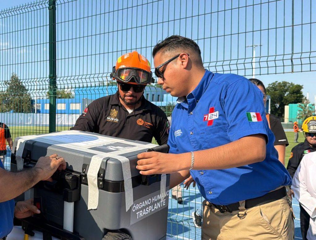 People in blue and black uniforms handling a gray medical cooler labeled ÓRGANO HUMANO TRANSPLANTE near a fence in bright outdoor light   Informe Regio