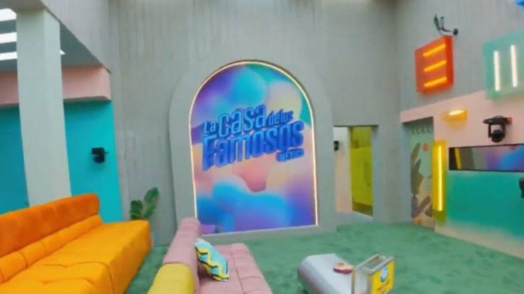 Colorful TV studio set with a pastel seating area and a curved doorway that reads La Casa de los Famosos in bold blue letters   Informe Regio