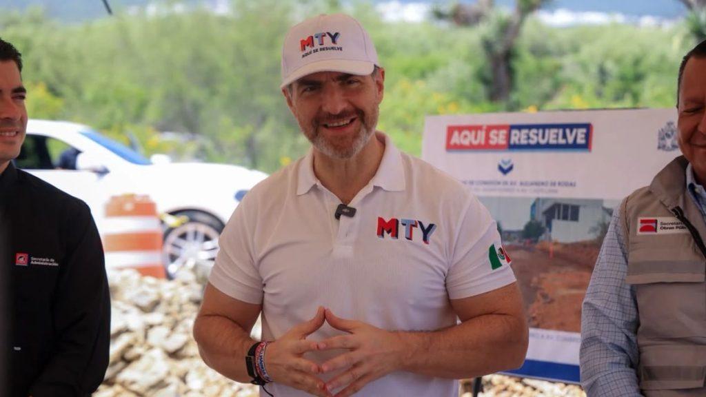 Smiling man in a white MTY polo and cap at an outdoor relief event hands joined with a banner that says AQUI SE RESUELVE in the background   Informe Regio