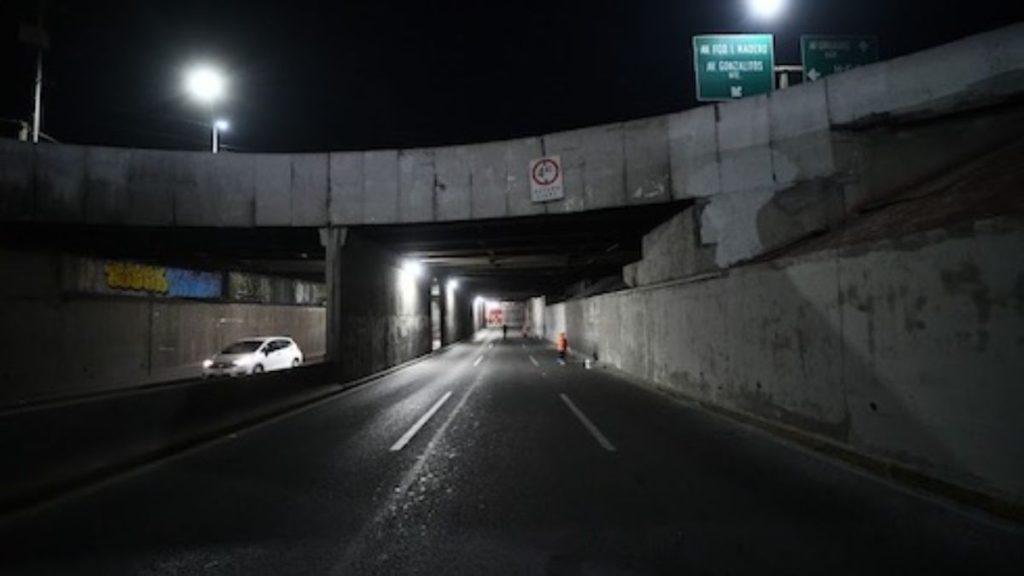 Night view of a dimly lit underpass with a white car on the left and a person in orange near the center   Informe Regio