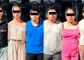 Six adults stand side by side with black bars over their eyes posing outdoors in casual clothing with a dark vehicle in the background   Informe Regio