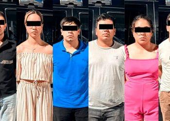 Six adults stand side by side with black bars over their eyes posing outdoors in casual clothing with a dark vehicle in the background   Informe Regio