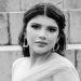 Portrait of a woman with dark hair in an off shoulder gown wearing statement earrings posed on concrete steps in black and white   Informe Regio