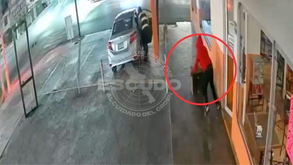 Escudo-monterrey-cae-joven-15-años - Informe Regio Pedestrian in a red shirt walks along a shopfront sidewalk pulling a wheeled suitcase as a car is parked on the street Informe Regio